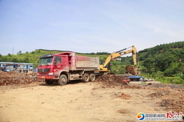 挖土機(jī)將挖出的泥土運(yùn)進(jìn)渣土車。