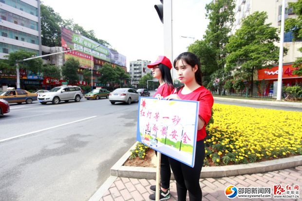 年輕的志愿者們認(rèn)真的舉著牌子站在路口，引導(dǎo)市民橫過馬路。
