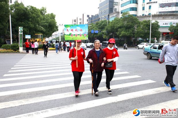 志愿者們扶老人過馬路。 