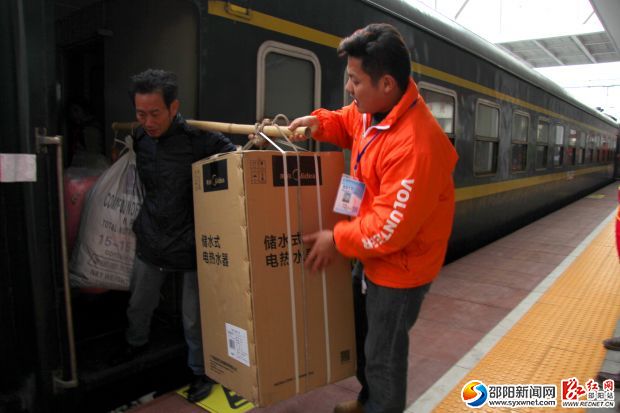 志愿者幫助農(nóng)民工老鄉(xiāng)將行李搬下車。