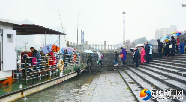 九江碼頭的中小學(xué)生排隊依次上船渡過資江，邵陽市地方海事局的工作人員正在現(xiàn)場進行指揮。