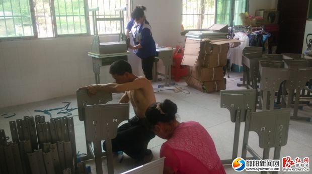 图为工人正在组装课桌
