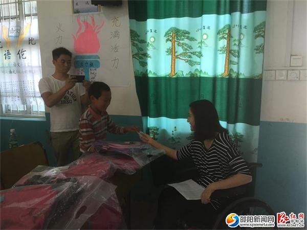 爱心大使梁艺为孩子们发放书包和助学金
