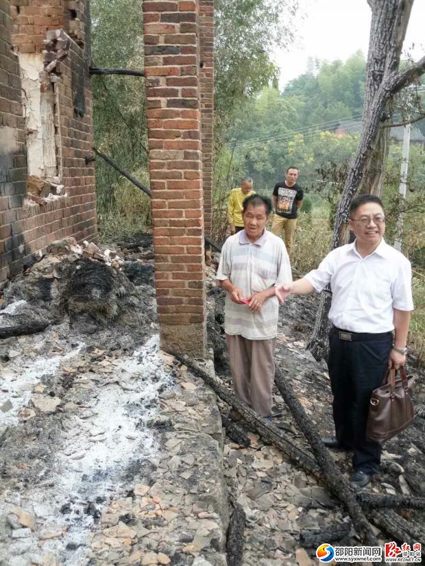 图为邵东农业银行领导在火灾现场将爱心款交到羊仲云手里