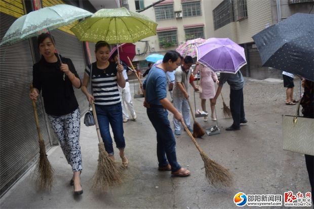 创文明卫生县城 干部职工冒雨清扫居民区