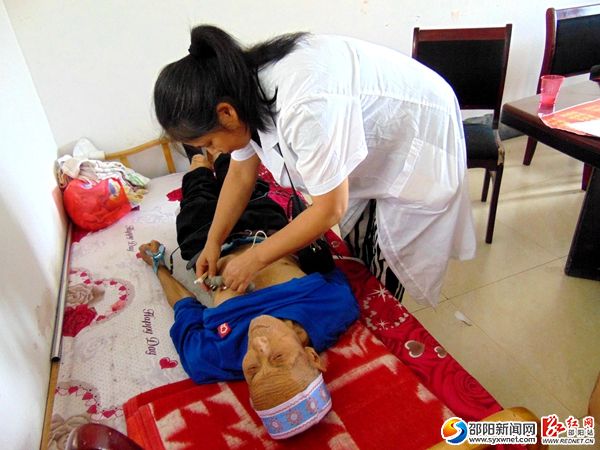 图为义诊医务人员为老人做心电图检查