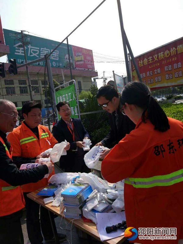 图为环卫局干部上街发放垃圾袋和文明手册