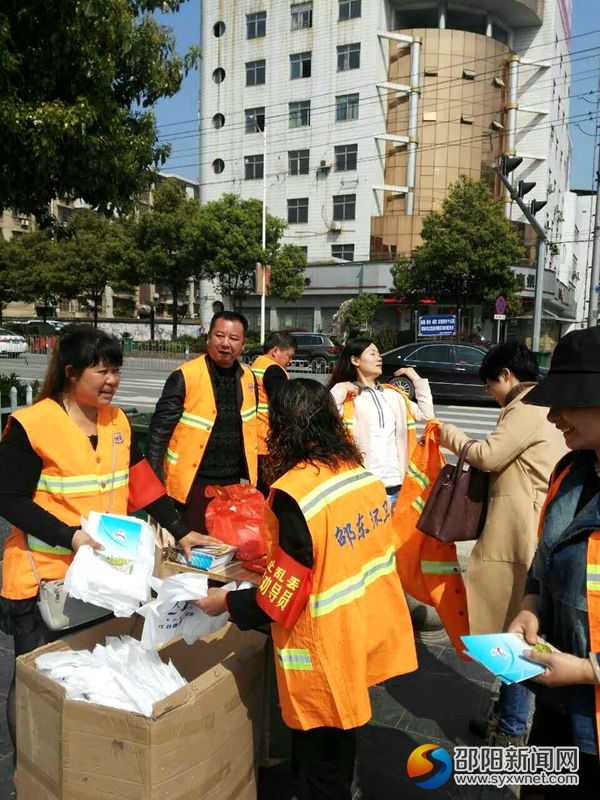 图为环卫局干部职工上街发放垃圾袋和文明手册