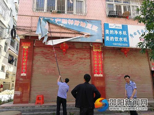 执法人员正在拆除有安全隐患的门店招牌