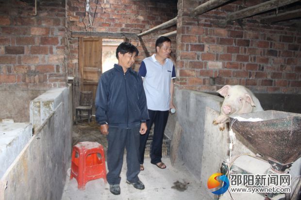 武冈卫计局党委副书记、副局长唐启智（左2）在贫困农户家现场了解养殖情况