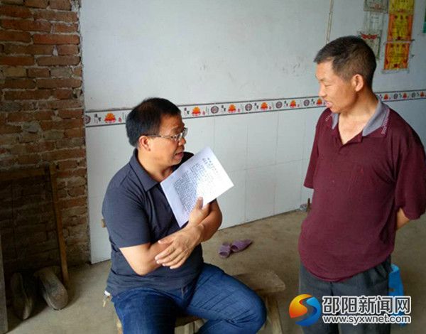 图为新邵一中校长李维勇与贫困户李召云交流
