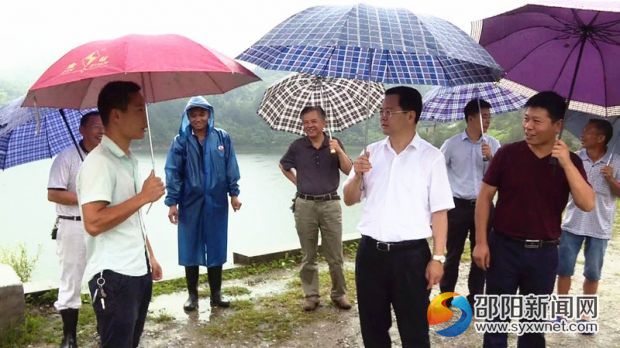 邵阳县委副书记、县长袁玉华(中)冒雨踏勘五峰铺镇江口亭水库防汛情况