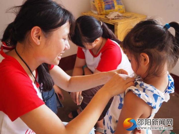 图为志愿者帮孩子整理衣裳