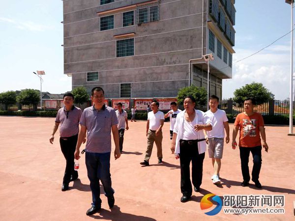 图为镇党委书记宁效龙带队参观云山村党建宣传栏