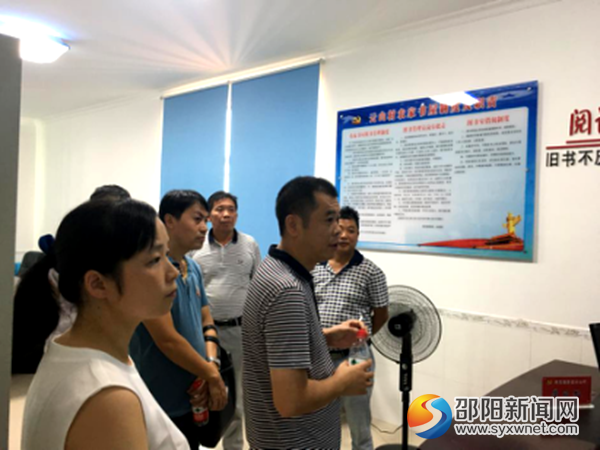 图为镇党委书记宁效龙(右一)在带队参观云山村的农家书屋