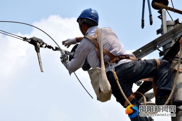 在绥宁县金屋塘镇，检修人员脸庞已被晒得黑里透红的电力施工人员，在烈日下对金屋镇10千伏金张线红万支线杆上的导线与瓷瓶进行更换。 (2)