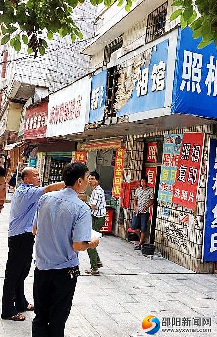 图为执法人员在排查门店招牌