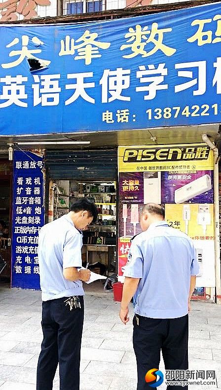 图为执法人员在排查门店招牌