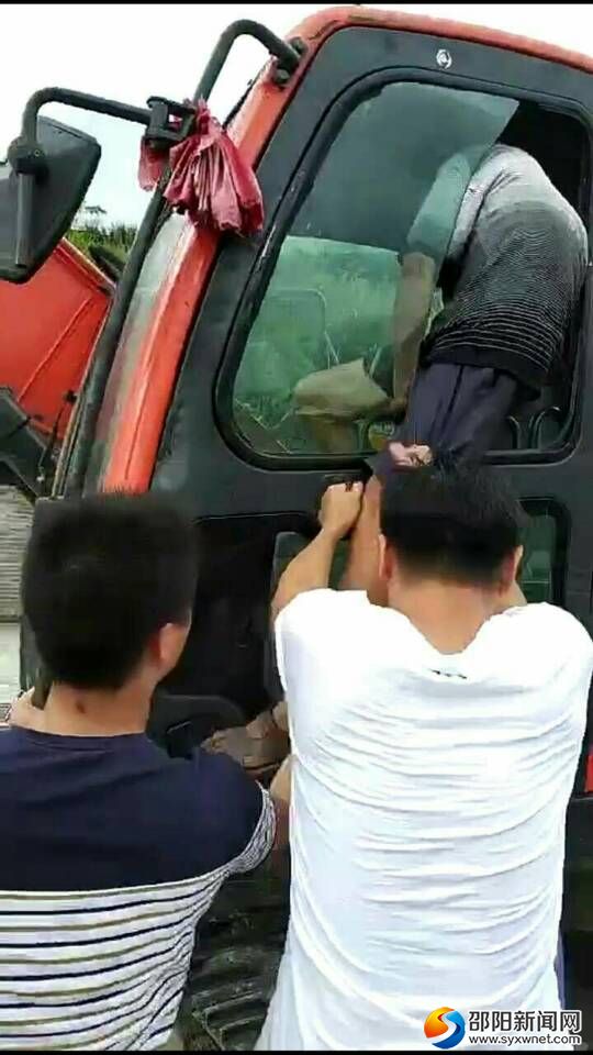 工作人员正在极力阻止李某爬上挖机
