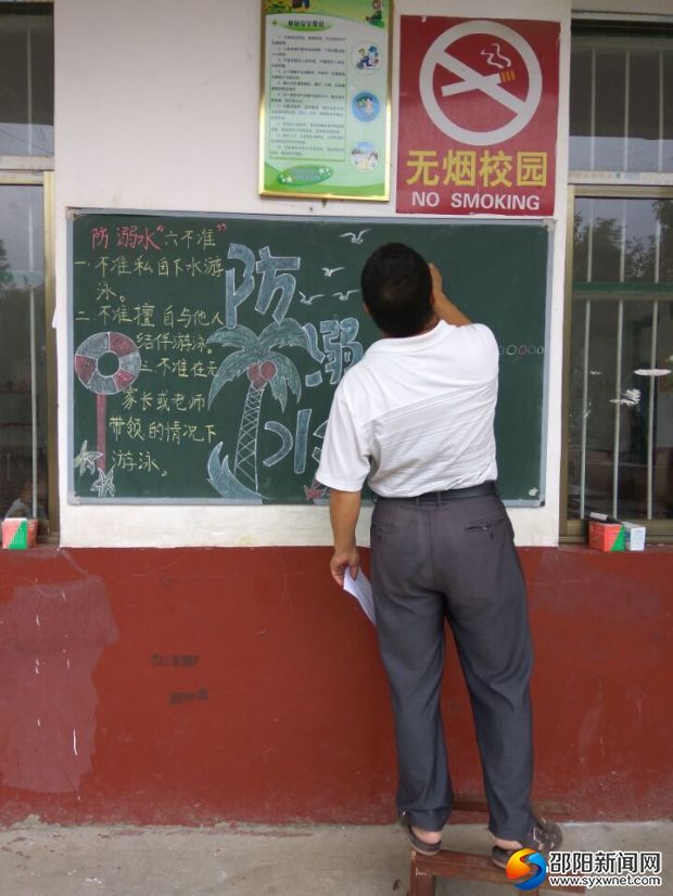 图为李开军校长正在精心设计板报