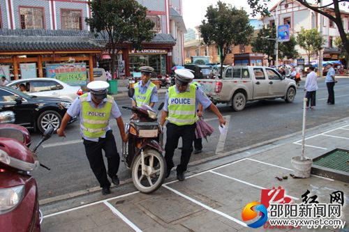 工作人员将乱停放摩托车摆放到停车位