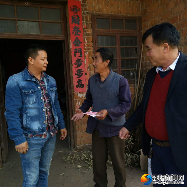 图为爱心人士、村干部将慰问金发放到特困户手中