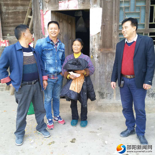 图为爱心人士、村干部将衣物发放到贫困户手中