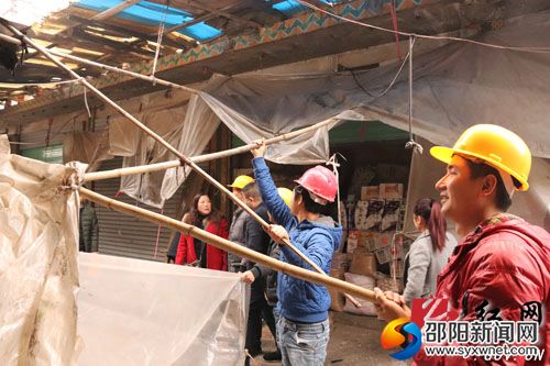 工作人员对市场内商铺违章搭建的雨棚进行拆除