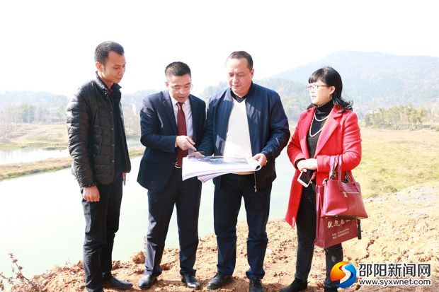 罗江坤在项目建设地与项目其他负责人商讨项目规划