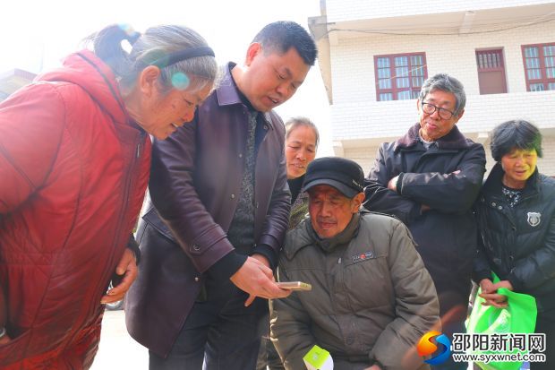 两市塘街道党工委书记李佑军（左二）为贫困人口讲解手机使用方法