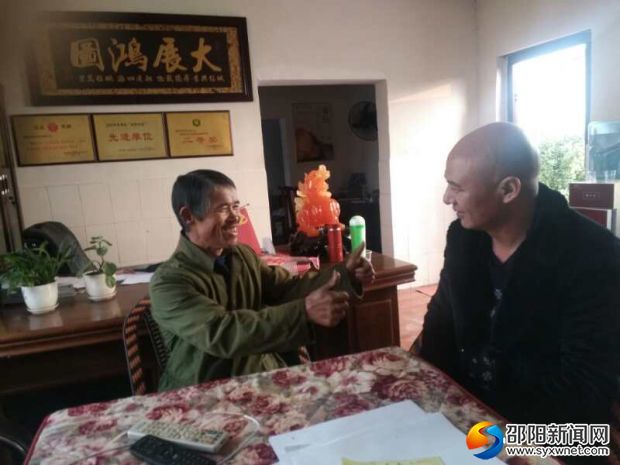 图为王波和十年如一日照顾的老人亲切交谈