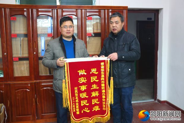 两市塘街道坝上新村村民张友成(右)将锦旗送到办事处主任李涛军手里。