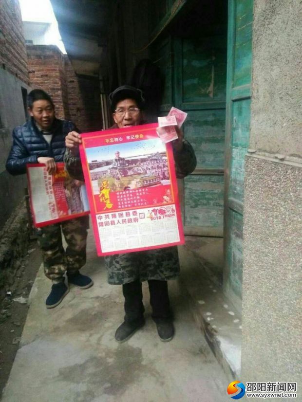 老退役军人展示领到的慰问金和年画
