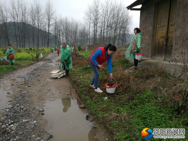新宁志愿者身穿雨衣冒雨清理河道垃圾
