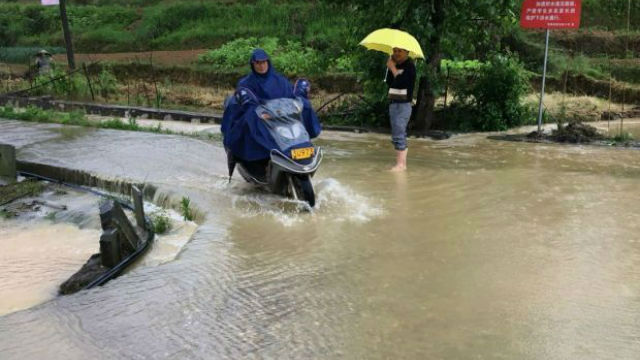 图为教师护送学生过水路