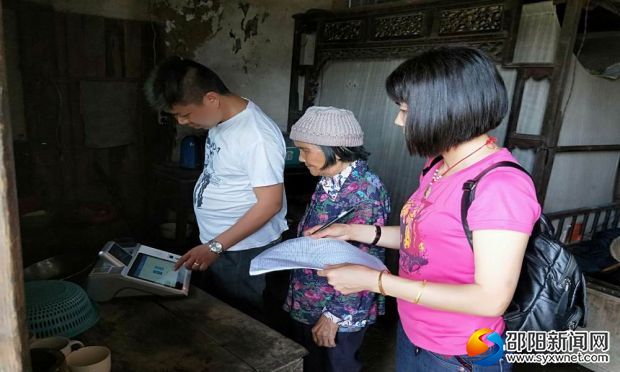 图为5月14日下午,工作人员正在滩底村刘和姣家里为老进行“人脸识别”身份认证。