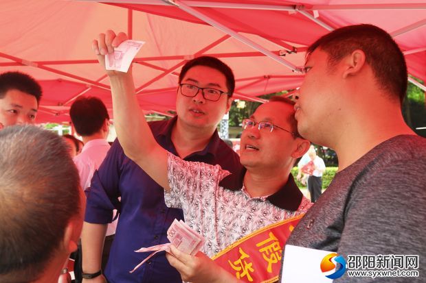 工作人员正在指导市民如何区分真假人民币
