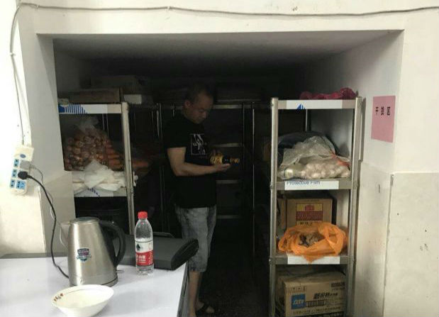 图为新邵县食品药品工商质量监督管理局工作人员正在检查学校食堂调味品。