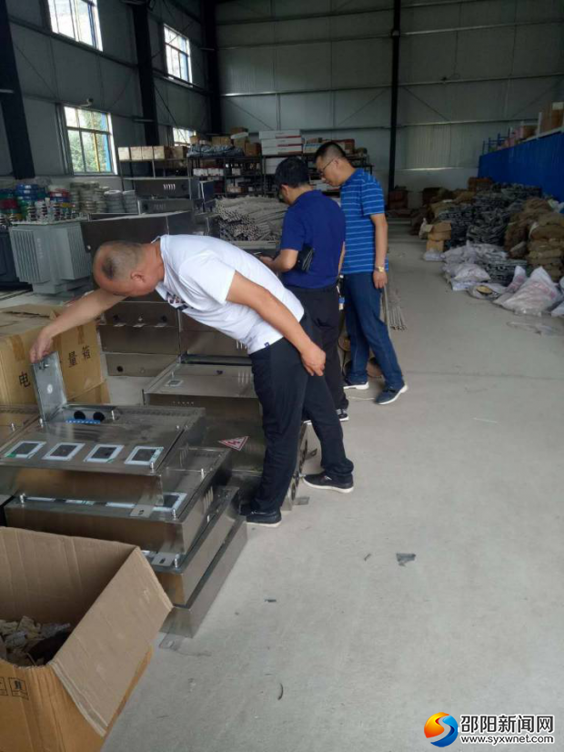 图为新邵县食品药品工商质量监督管理局工作人员在检查变电箱。