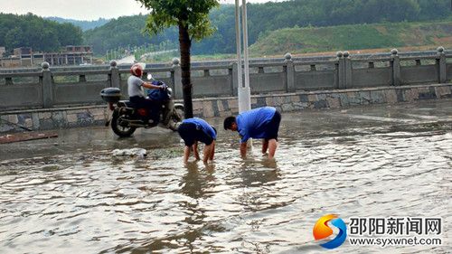 城管局执法人员正在清理雨水井口周边垃圾