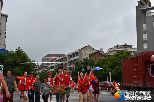 志愿者热心帮老人挑担子文明过斑马线