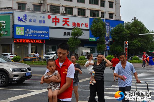 来自该校516班志愿者给行人抱孩子过斑马线