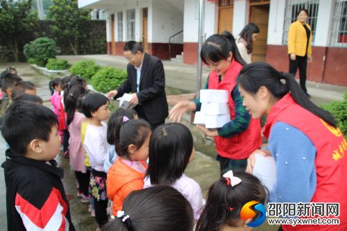 图为社工和五团镇领导为学生发放杯子