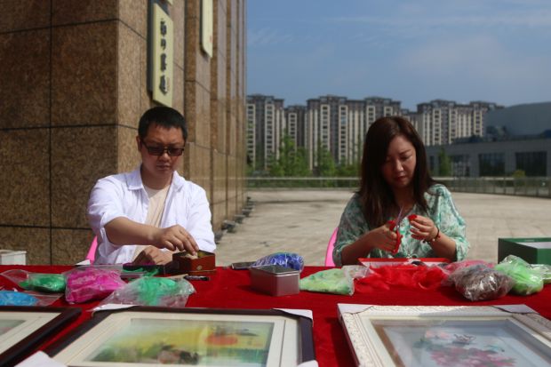 邵阳羽毛画传承人何迁（图左）、何芃（图右）在展示制作技艺