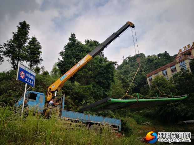 (6月27日整治行动现场,吊车将竹筏吊出水面。)
