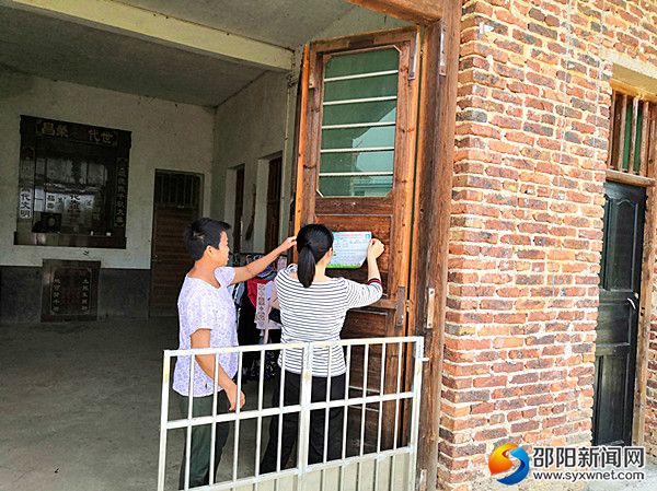 帮扶责任人(右)在对象户门上粘贴家庭医生签约服务明白卡