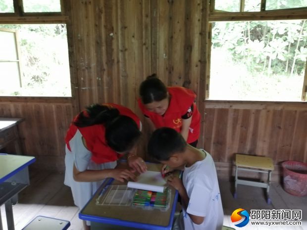 图为志愿者辅导孩子画画