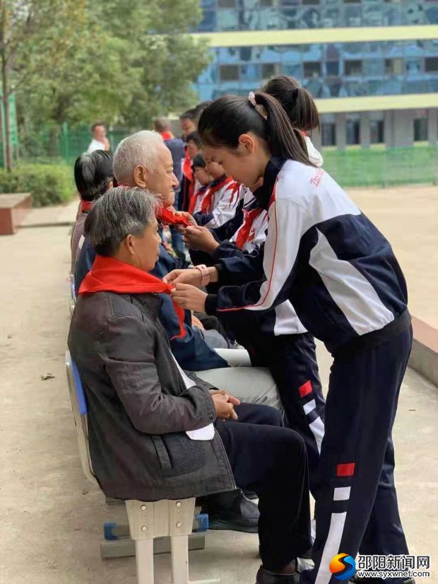 少先队员代表给退休教师们戴红领巾