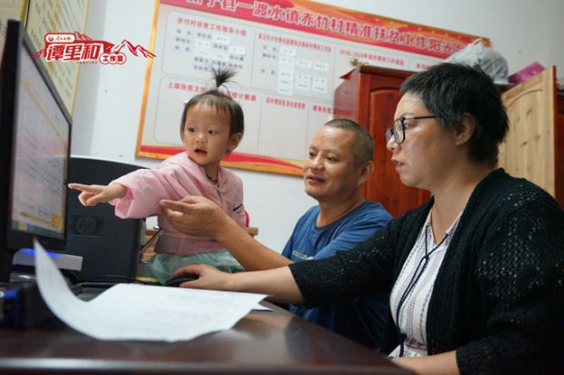国庆前夕,吴晓芳在村部帮吉刚上传扶贫资料到电脑上。
